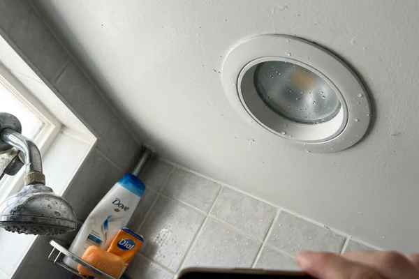 Sealed-lens wet-location potlight in a shower ceiling