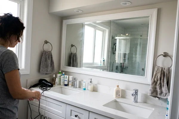 Double vanity lit by potlights in front of the mirror
