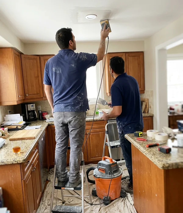Two installers patching drywall around a new potlight
